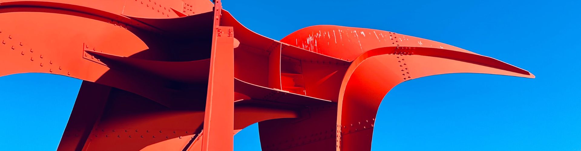 Photo of Alexander Calder's The Eagle, 1971. A bright red iron sculpture against a clear blue sky.